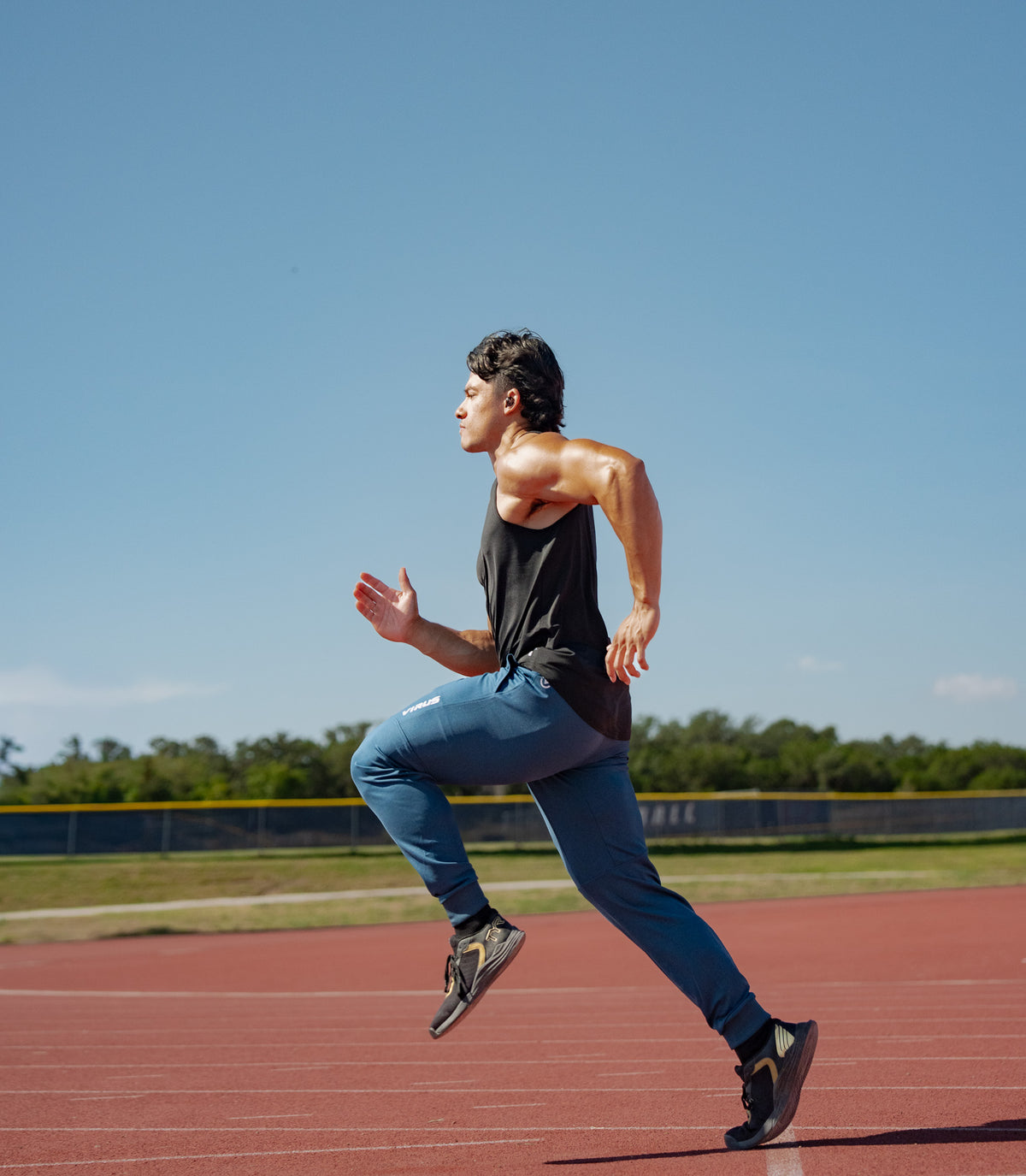 Male athlete in VIRUS® performance gear sprinting on a track.
